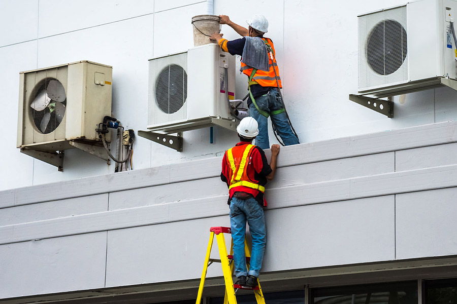 two workers checking hvac units